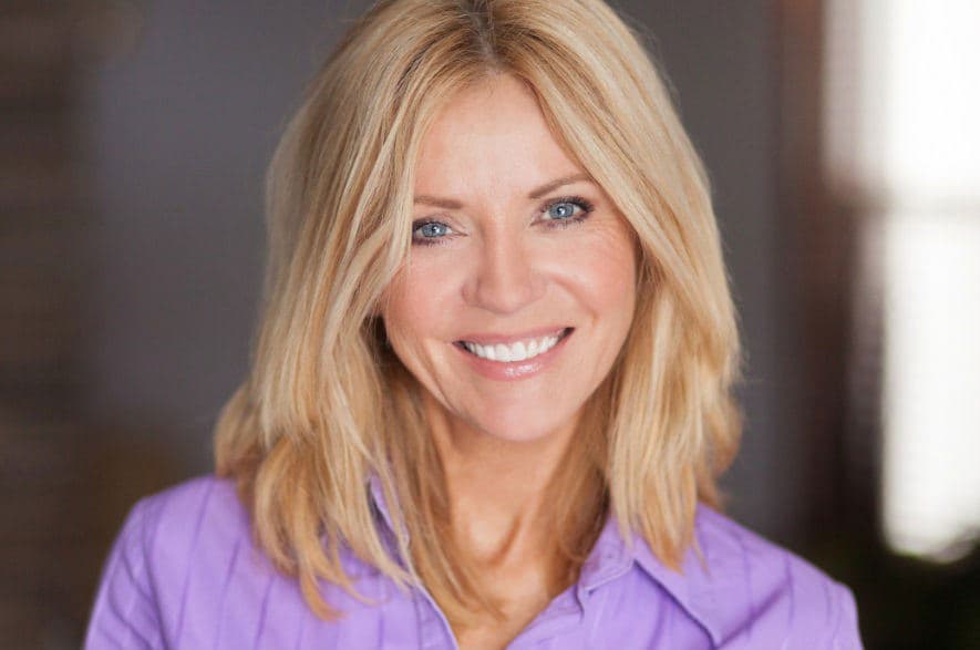 Blonde woman in purple button up blouse smiling